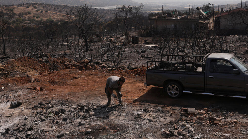 Giannis Triantafyllou,22, cleans metal debris from his cousin Giannis Routis', 35, house backyard following a wildfire in Mandra, Greece on July 21, 2023.